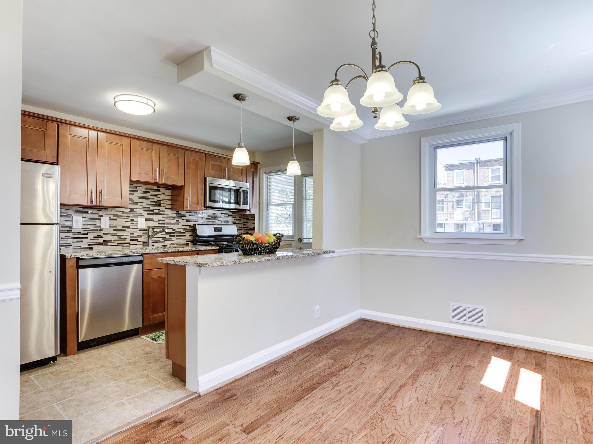 4400 Eldone Road Baltimore, MD 21229 - Photo 10 of 30 a kitchen with stainless steel appliances granite countertop a sink a microwave oven a refrigerator with white cabinets and wooden floor