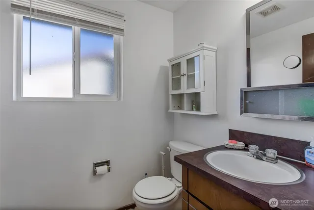 a bathroom with a toilet sink a mirror and vanity