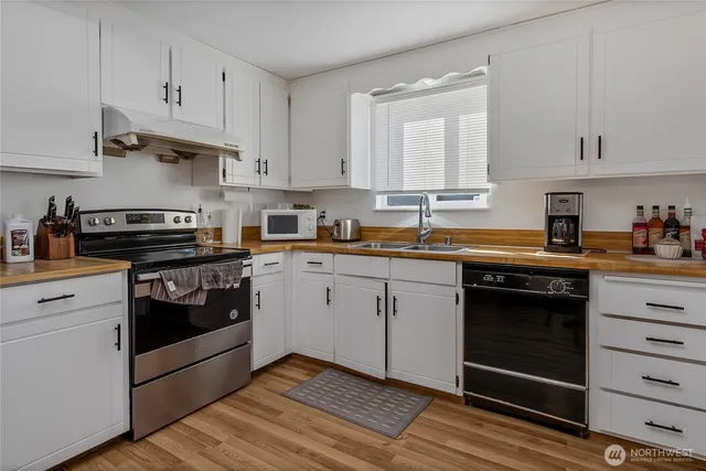 a kitchen with cabinets stainless steel appliances a sink and wooden floor