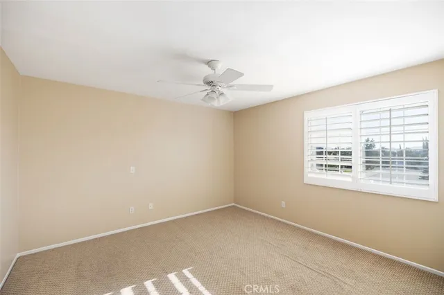 an empty room with a window and a ceiling fan