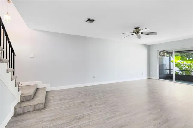 a view of an empty room with a window and wooden floor