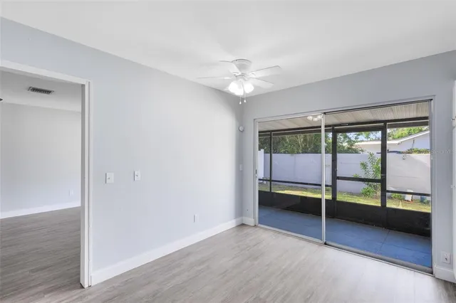 an empty room with chandelier fan and windows