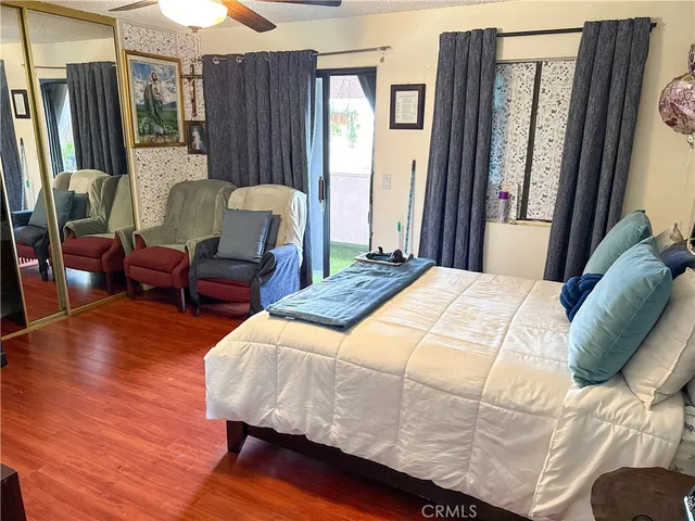 a bedroom with a bed wooden floor and a large window