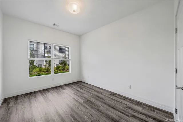 an empty room with wooden floor and window