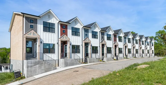 a view of a white house with large windows and a small yard