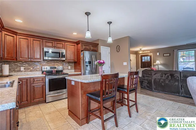 a kitchen with stainless steel appliances granite countertop a stove top oven a sink dishwasher a dining table and chairs with wooden floor