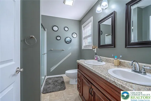 a bathroom with a granite countertop sink a toilet a mirror and shower