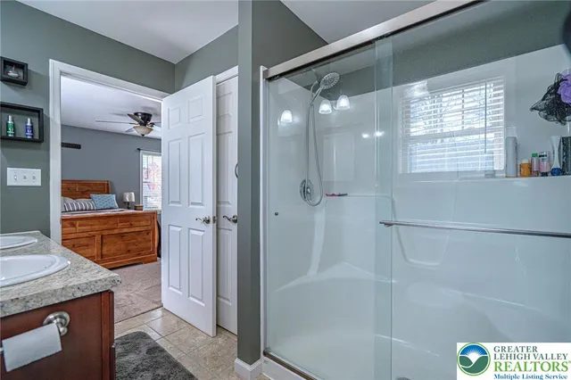 a bathroom with a granite countertop shower a sink and a mirror