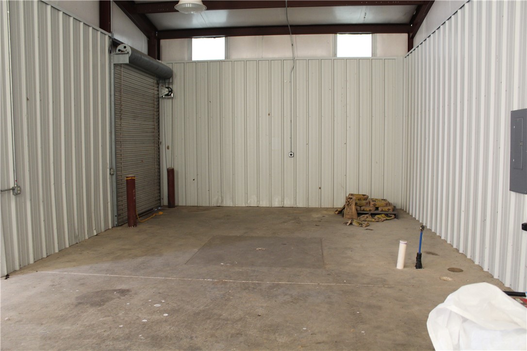 158 Ragon Road Tilly, AR 72679 - Photo 26 of 51 Spacious interior featuring concrete flooring, corrugated metal walls, and a large roll-up door