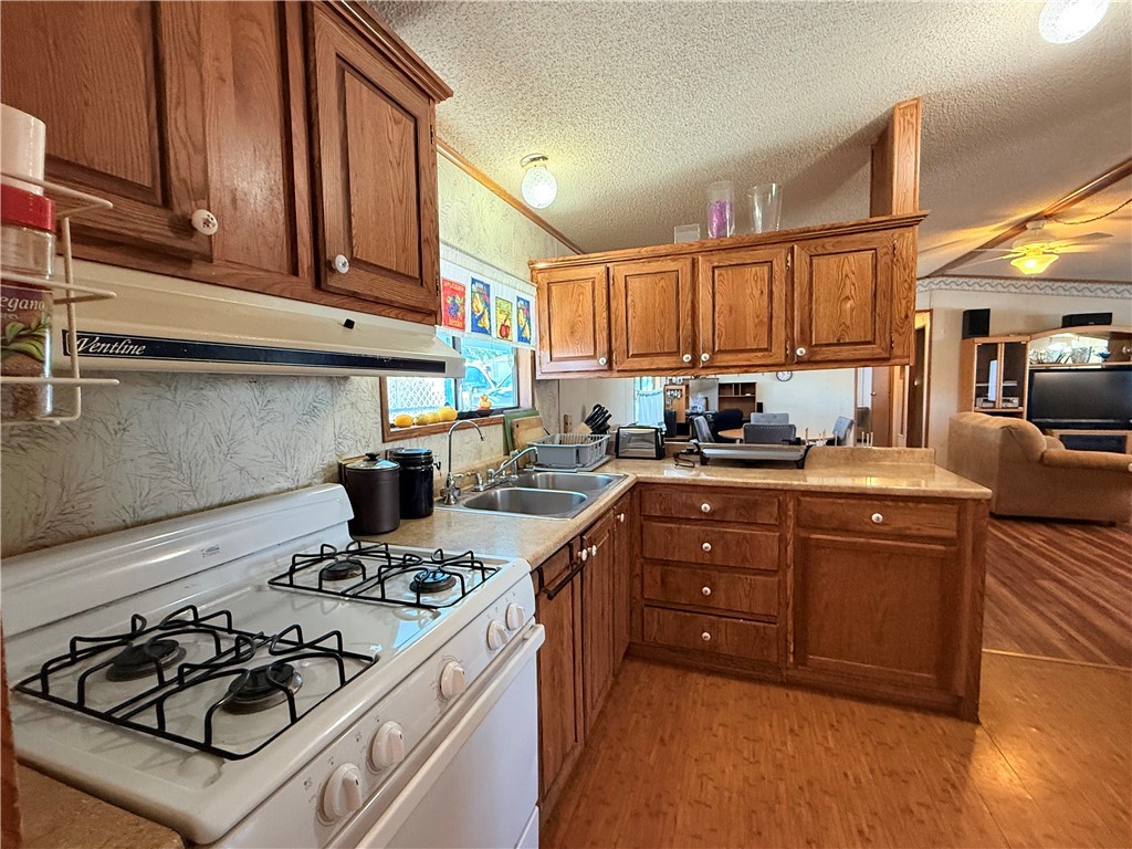 1637 Talc Road Bullhead City, AZ 86442 - Photo 37 of 37 Kitchen with white gas range, light countertops, open floor plan, crown molding, and brown cabinets