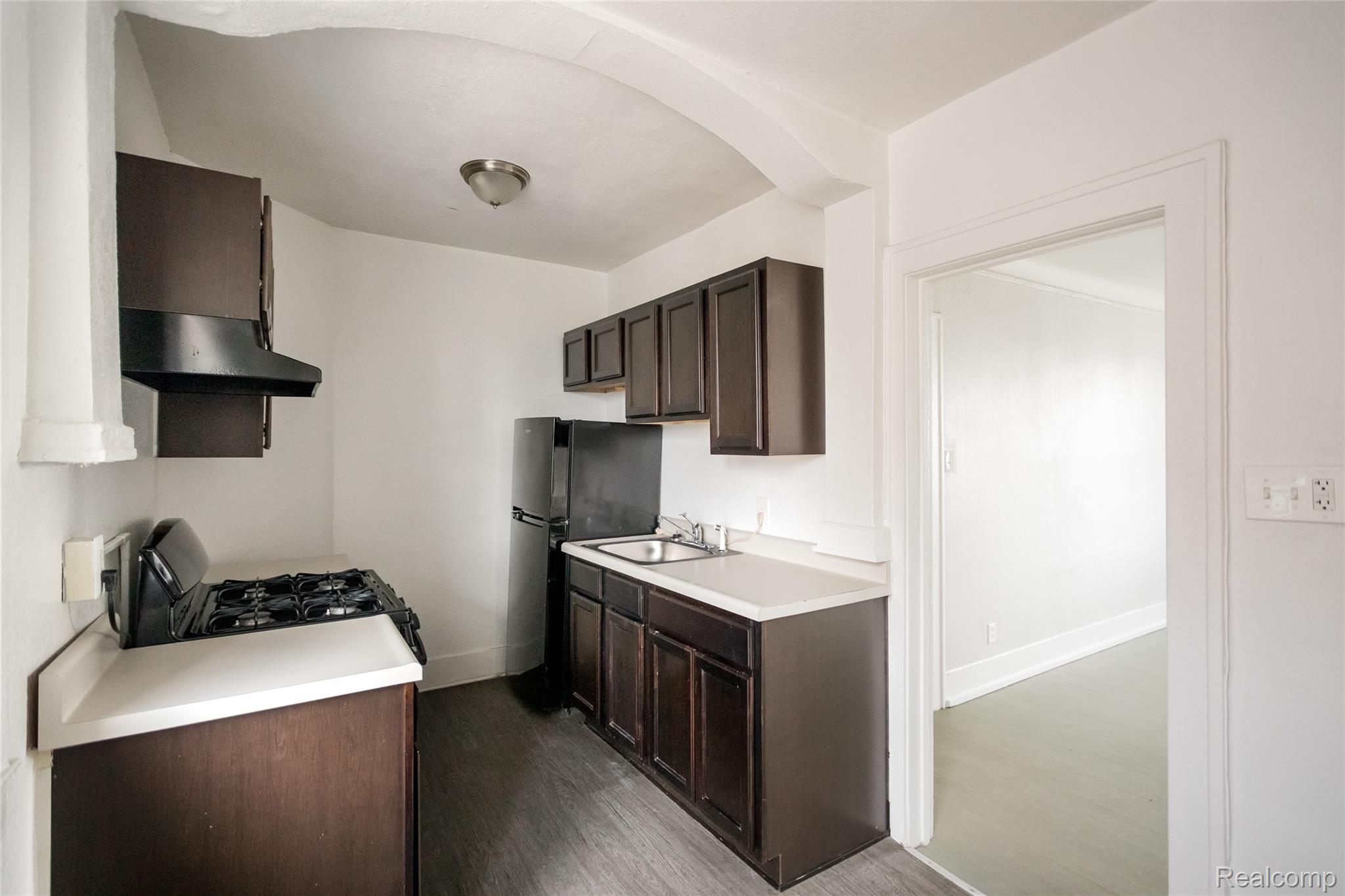 2683 Central Street Detroit, MI 48209 - Photo 6 of 10 Kitchen with dark wood finish cabinets, light countertops, black appliances, and dark wood-style floors