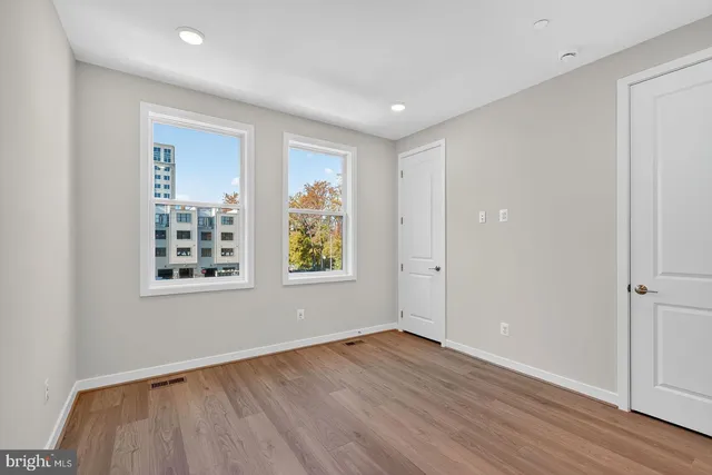 an empty room with wooden floor and windows