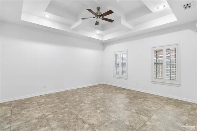 an empty room with chandelier fan and windows