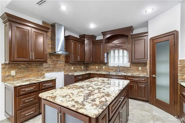 a kitchen with kitchen island granite countertop wooden cabinets and a refrigerator