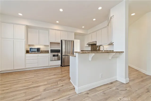 a kitchen with stainless steel appliances granite countertop a refrigerator a stove a sink and a microwave