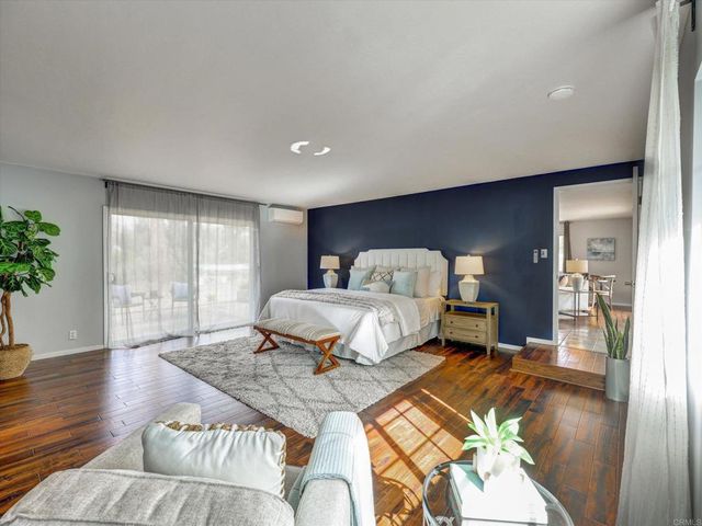 a spacious bedroom with a bed and wooden floor