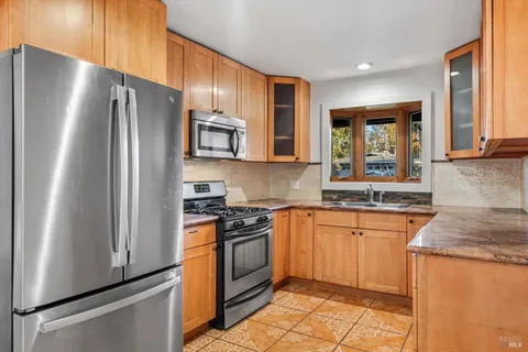 a kitchen with stainless steel appliances granite countertop a refrigerator stove top oven and sink
