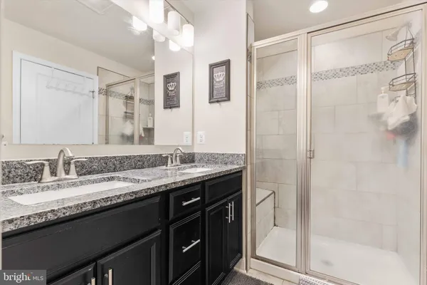 a bathroom with a granite countertop sink a mirror and a shower