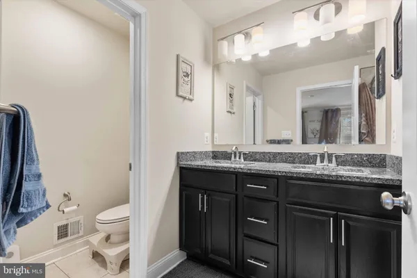 a bathroom with a granite countertop toilet a sink a mirror and a shower