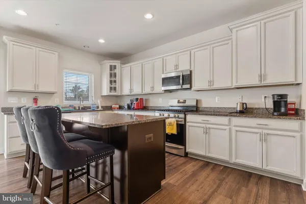 a kitchen with stainless steel appliances granite countertop a sink a stove a window and white cabinets