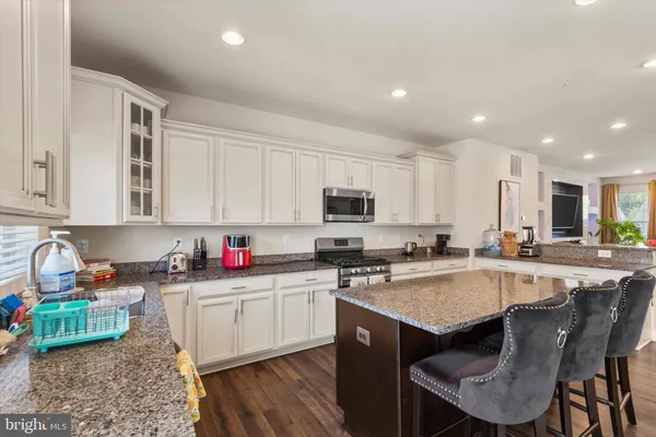 a kitchen with stainless steel appliances granite countertop a table chairs sink refrigerator and cabinets