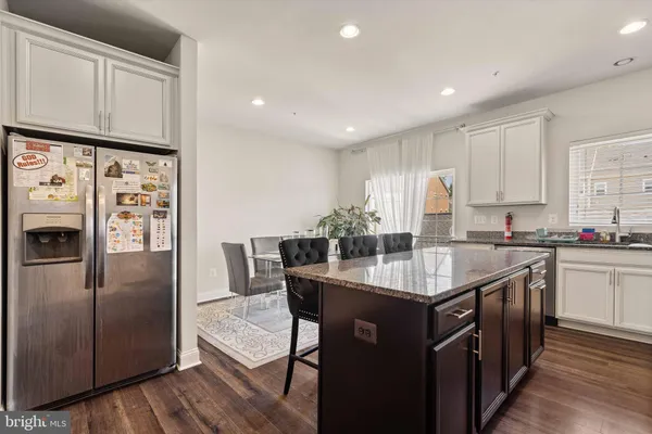 a kitchen with stainless steel appliances granite countertop a kitchen island a stove a refrigerator a sink and white cabinets