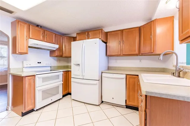 a kitchen with granite countertop white cabinets and white appliances