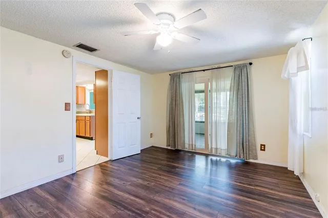 a view of an empty room with window and wooden floor
