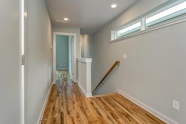 a view of a hallway with wooden floor and staircase