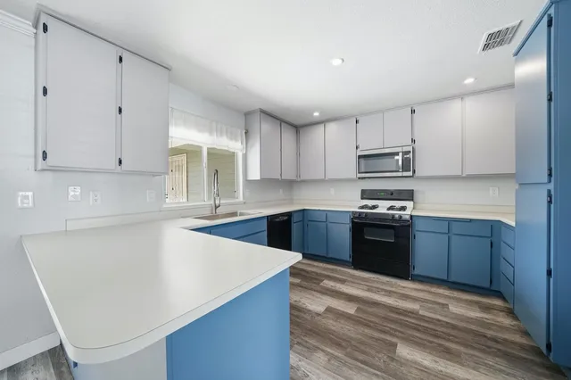 a kitchen with stainless steel appliances granite countertop a stove a sink and a microwave