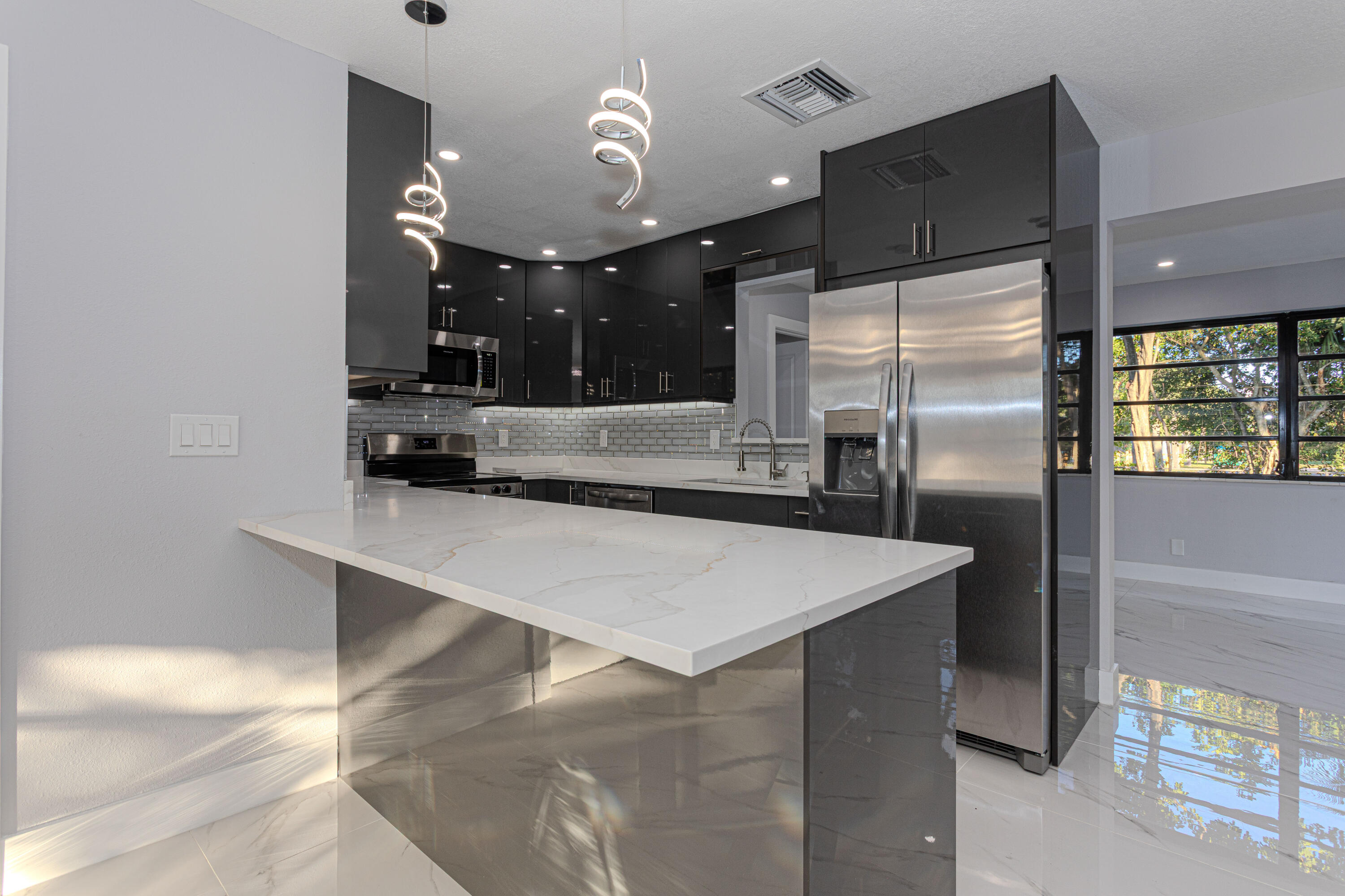 62 Andros Road Palm Springs, FL 33461 - Photo 9 of 41 a kitchen with kitchen island a counter top a refrigerator and a sink