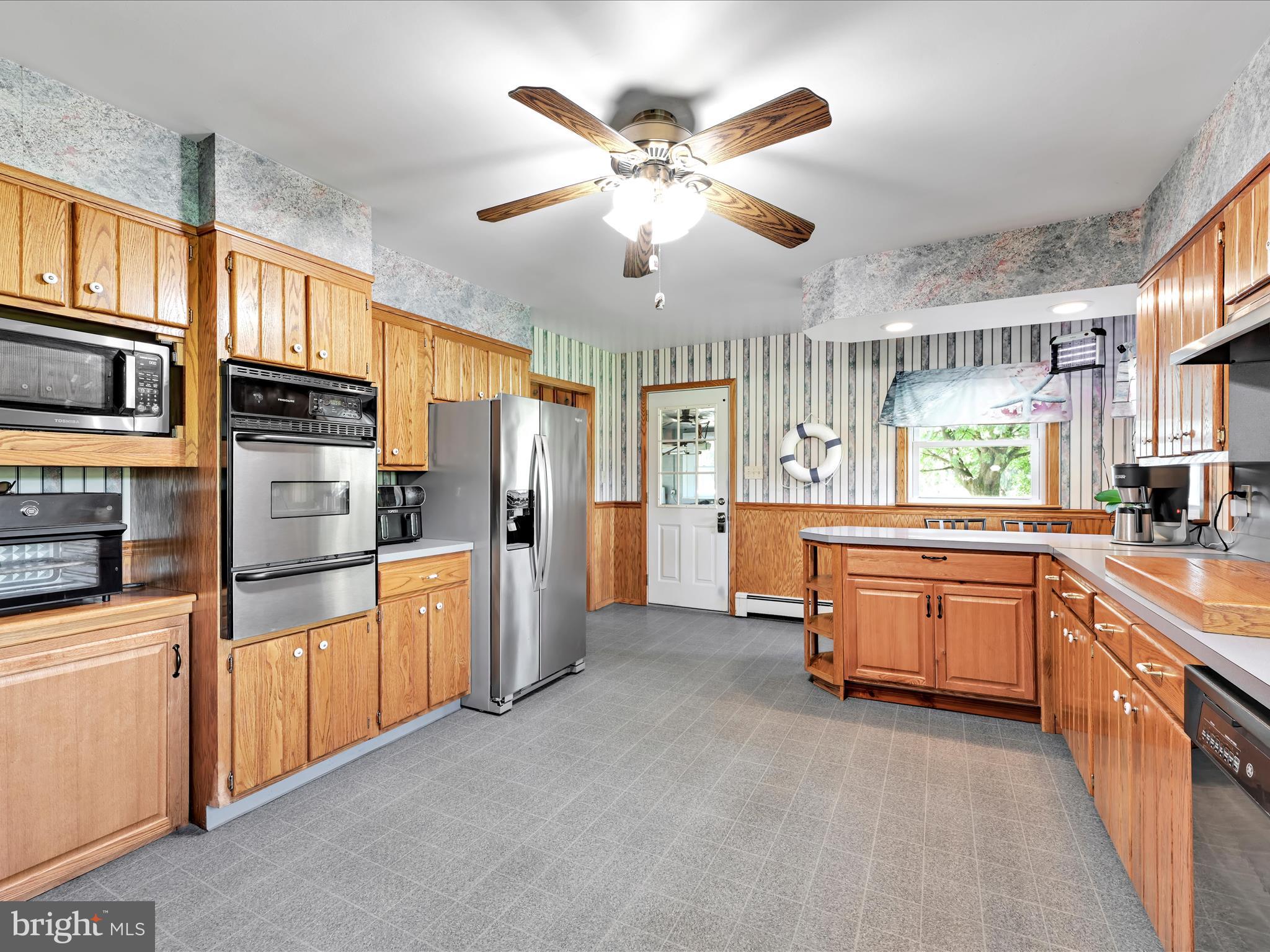 7932 Jonestown Road Harrisburg, PA 17112 - Photo 11 of 79 a kitchen with stainless steel appliances kitchen island granite countertop a refrigerator a stove a sink dishwasher a dining table and chairs with wooden floor