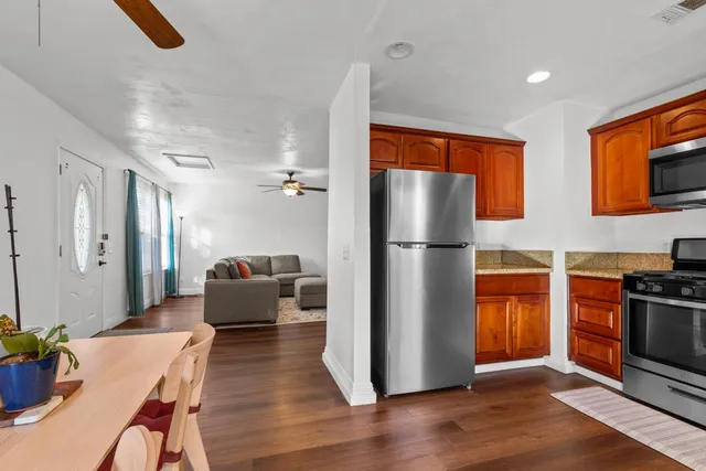 a kitchen with stainless steel appliances granite countertop a refrigerator a stove a sink dishwasher and a refrigerator with wooden floor