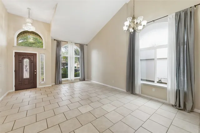 a view of an empty room with window and chandelier fan
