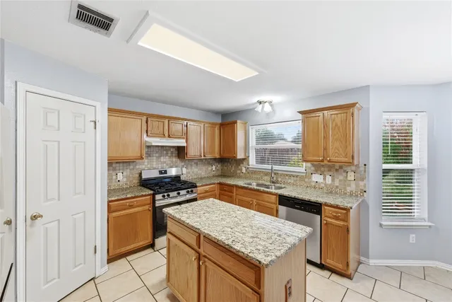 a kitchen with stainless steel appliances granite countertop a stove a sink and a refrigerator