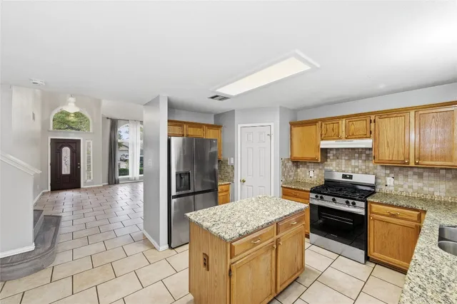 a kitchen with stainless steel appliances granite countertop a stove a sink dishwasher and a refrigerator with white cabinets