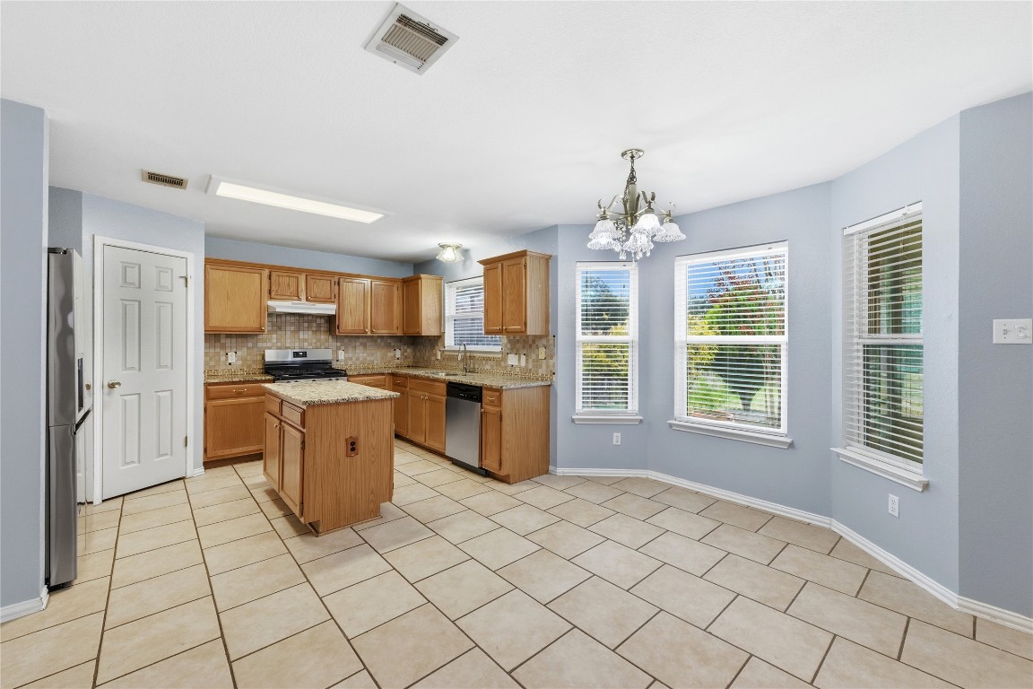 910 Kirtomy Loop Pflugerville, TX 78660 - Photo 27 of 37 a kitchen with stainless steel appliances granite countertop a stove a sink dishwasher and a refrigerator with white cabinets