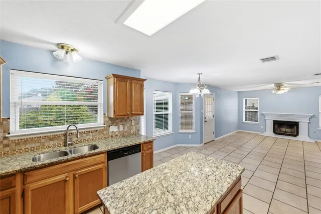 a open kitchen with granite countertop a sink dishwasher a stove and a dining table with wooden floor