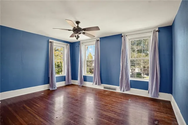 a view of an empty room with window and wooden floor