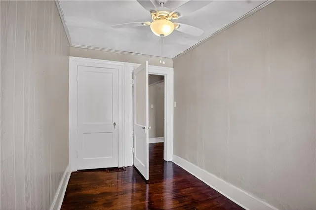 an empty room with wooden floor and a ceiling fan