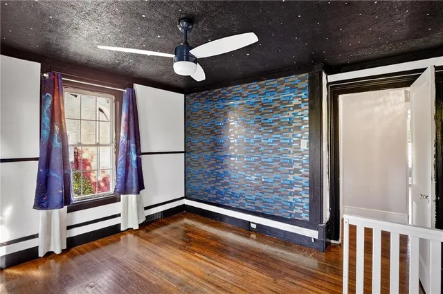 a view of an empty room with a window and wooden floor