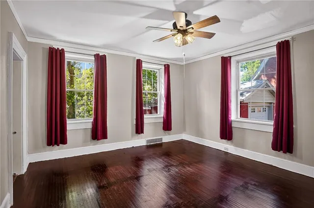 a view of an empty room with a window and wooden floor