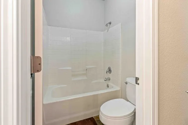 a white toilet sitting next to a bath tub