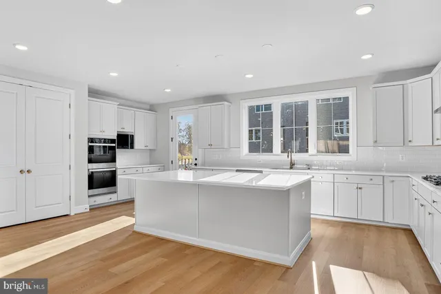 a large kitchen with kitchen island a sink stainless steel appliances and cabinets