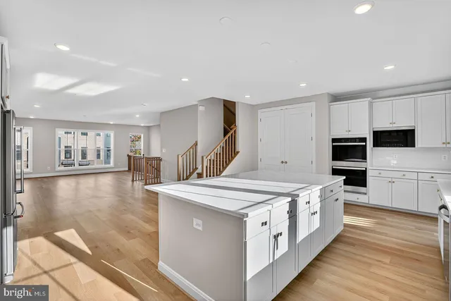 a large white kitchen with stainless steel appliances granite countertop a stove and a sink