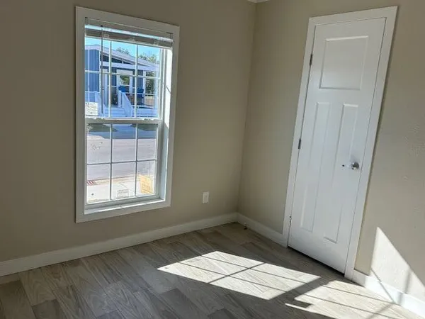 an empty room with wooden floor and windows