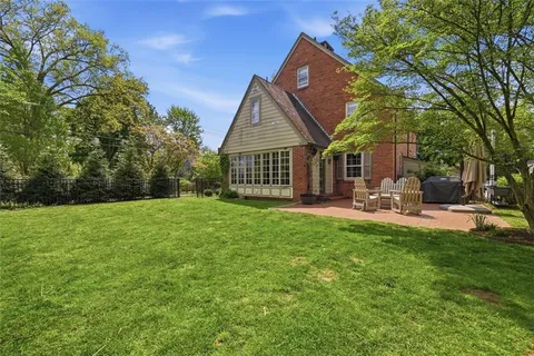 a backyard of a house with table and chairs plants and large tree