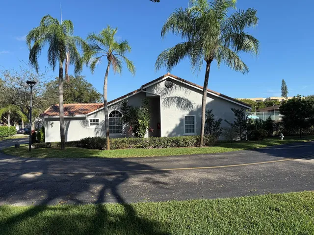 a view of a house with a yard and palm trees