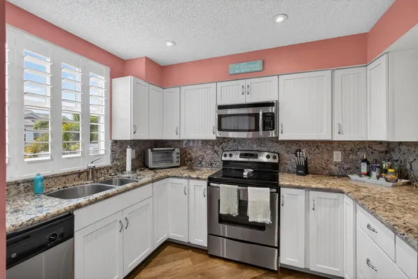 a kitchen with granite countertop a sink stove and cabinets