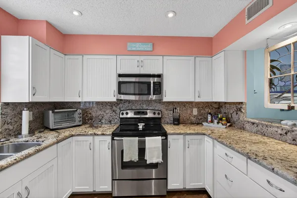 a kitchen with stainless steel appliances granite countertop a sink stove and cabinets